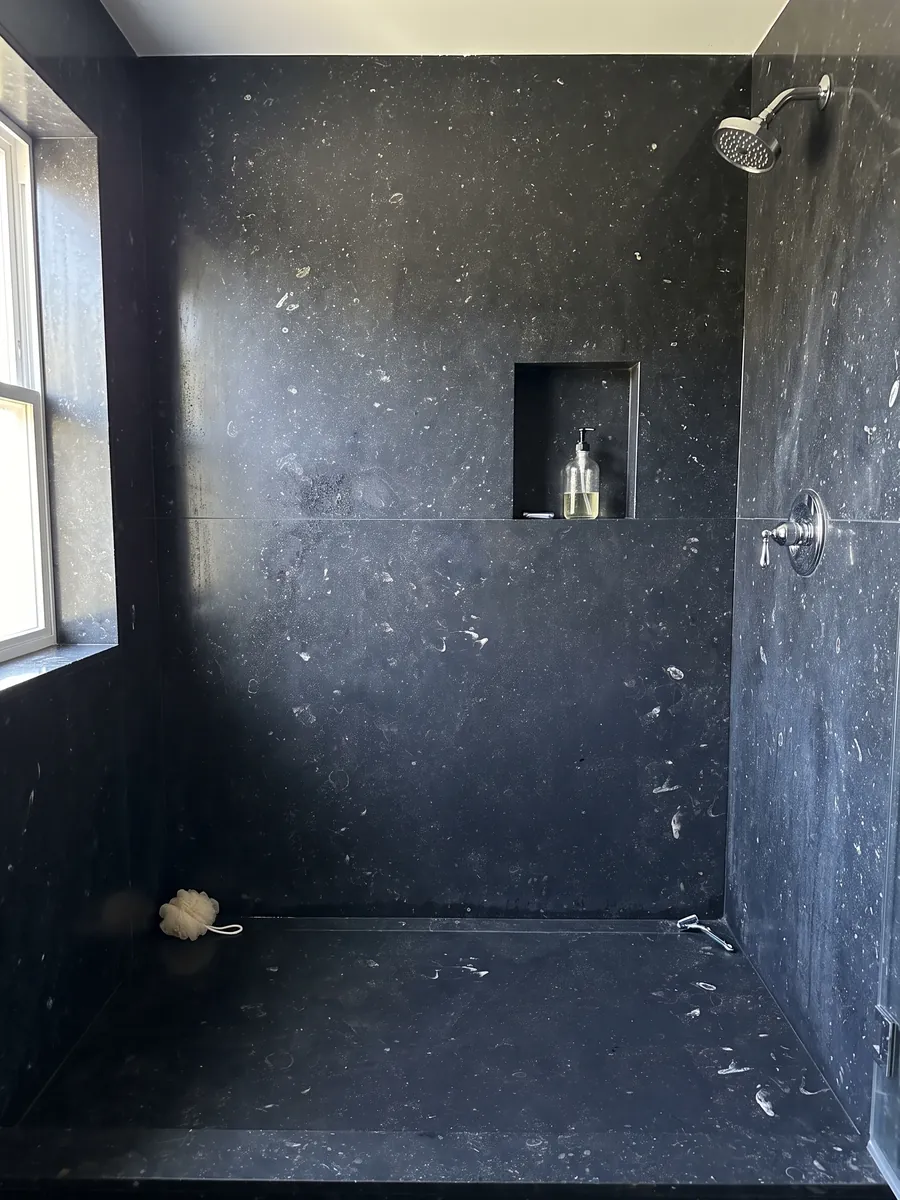 Shower lined with full slabs of black Pierre Bleu marble with a recessed niche: bluish black with small scattered light flecks