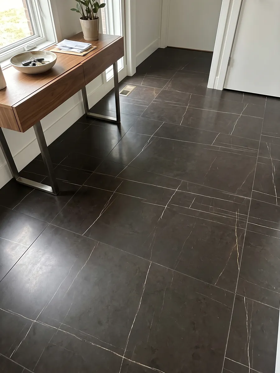 Entryway floor in large slabs of Sahara Noir black marble with natural light: brown-black with very fine, straight, sparse gold lines