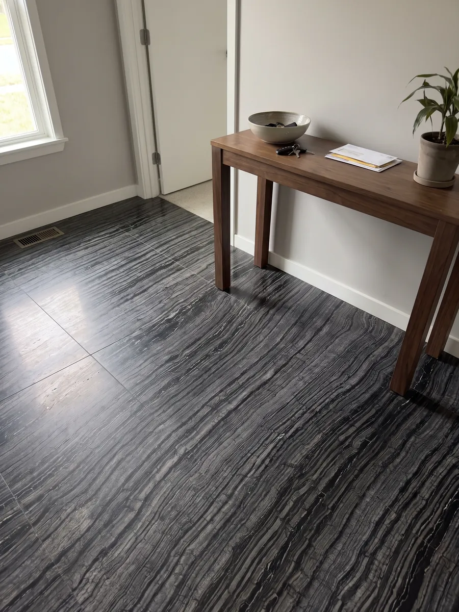 Entryway floor in large slabs of black Zebrato marble with natural light: black with fine, wavy gray stripes running in diagonal, bark-like effect