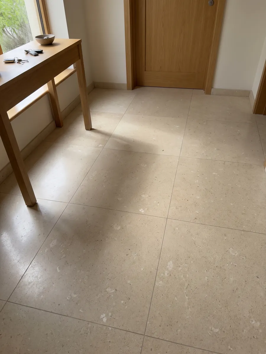 Entryway floor in large Pietra di Vicenza Bianca marble slabs with natural light: sandy beige with visible grain and small light fragments