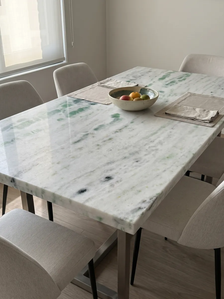 Dining table with a Pinta Verde marble top on a steel base: white with horizontal bands splashed with emerald green patches