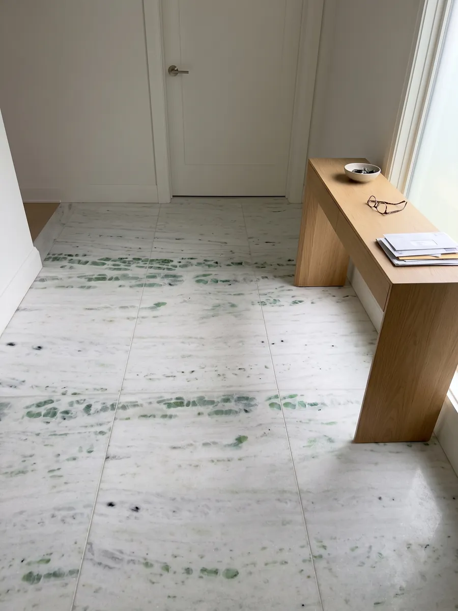 Entryway floor in large Pinta Verde marble slabs with natural light: white with horizontal bands splashed with emerald green patches