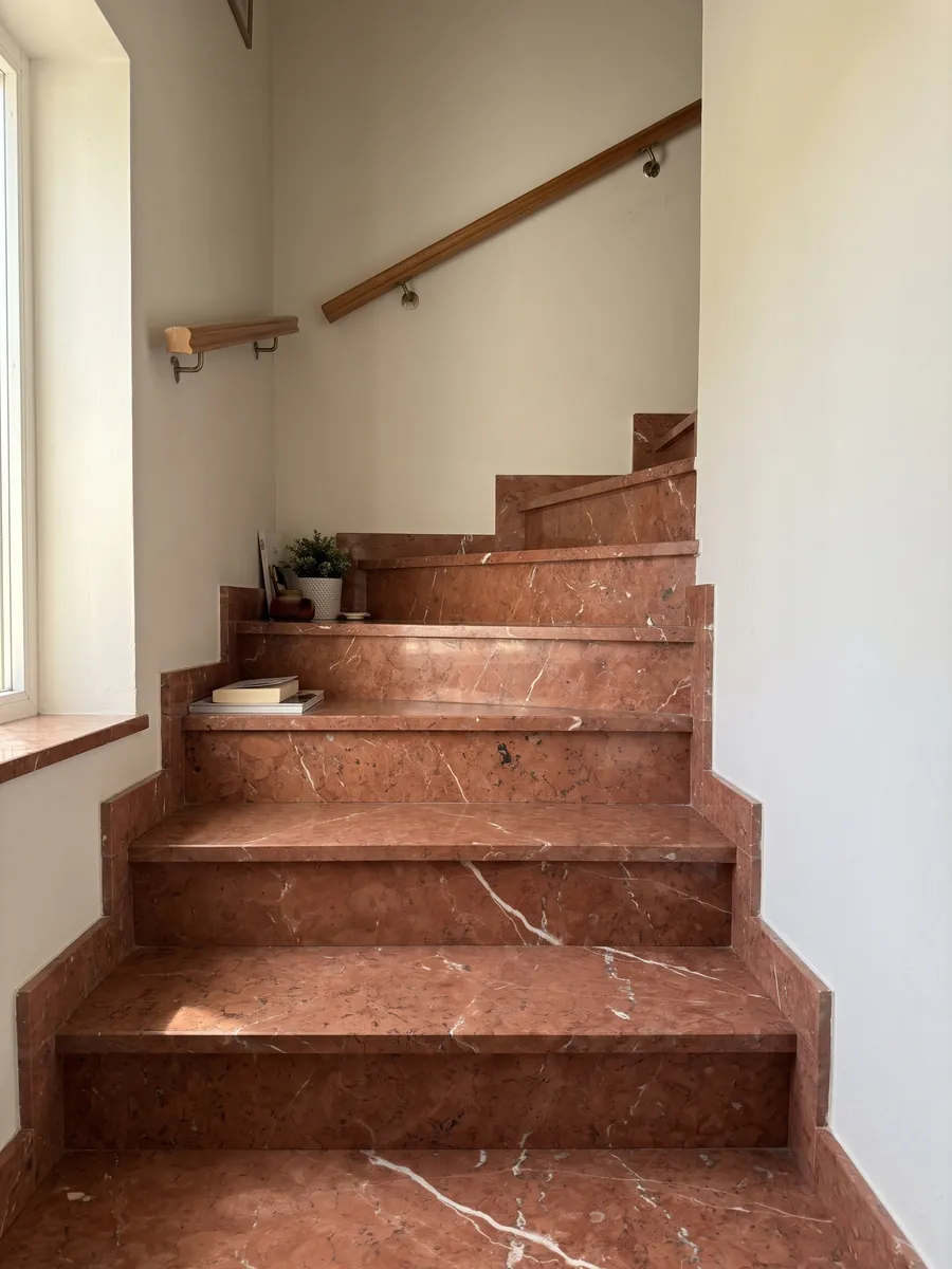 Interior staircase with Rojo Alicante marble treads and a handrail: even terracotta red crossed by a few diagonal white veins