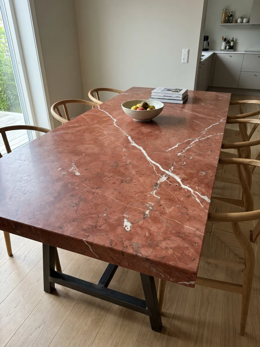 Dining table with a Rojo Alicante marble top on a steel base: even terracotta red crossed by a few diagonal white veins
