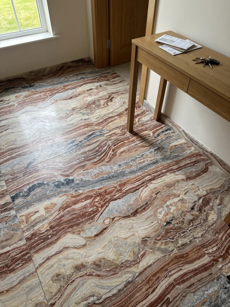Entryway floor in large slabs of red Arabescato Rosso marble with natural light: wavy horizontal bands of brick red, cream and gray, with black spots at the top