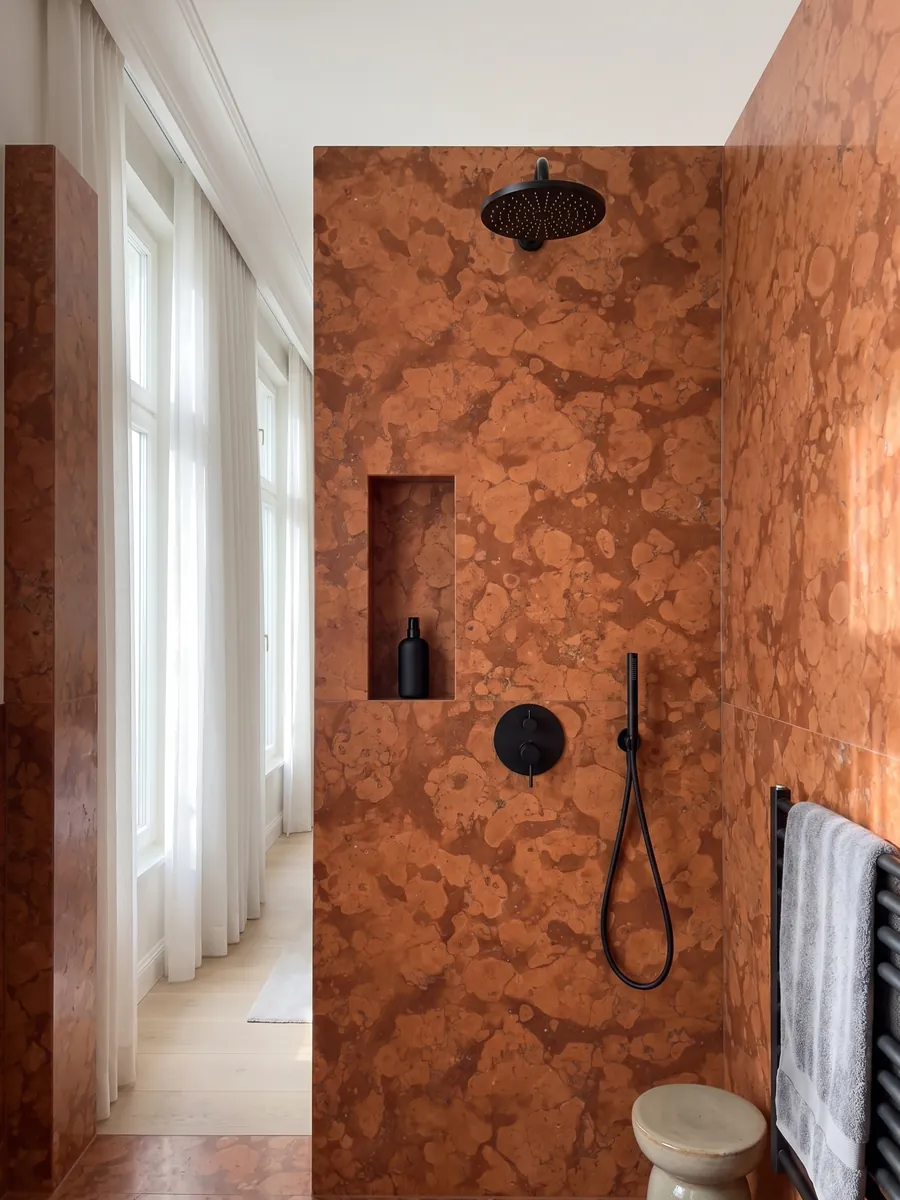Shower clad in full Rosso Asiago marble slabs with a recessed niche: reddish orange with light rounded patches over a darker background