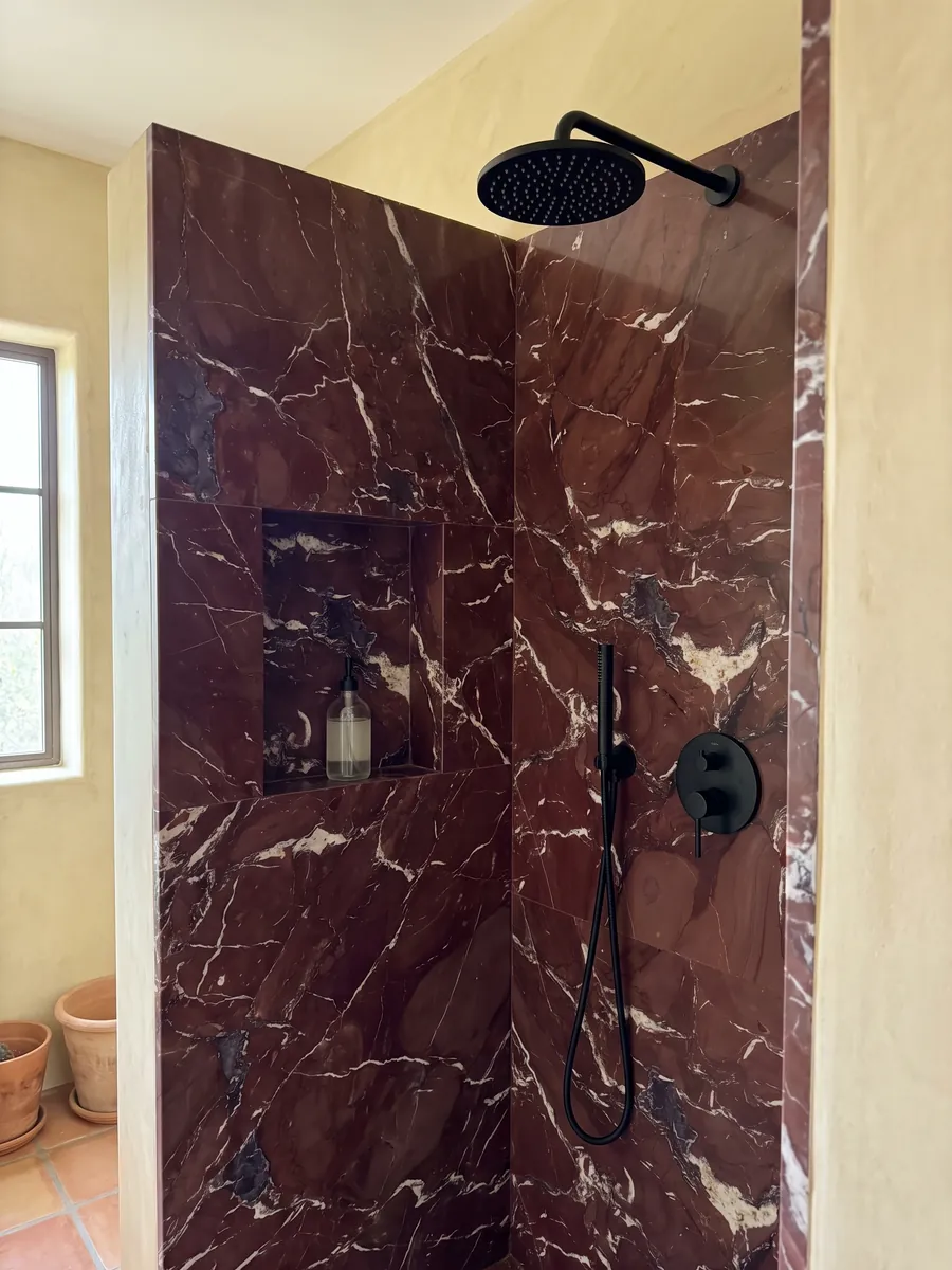 Shower clad in whole Rosso Cardinale marble slabs with a recessed niche: burgundy red with irregular white veins and some gray-violet stains