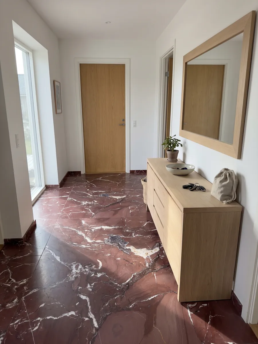 Entryway floor in large Rosso Cardinale marble slabs with natural light: burgundy red with irregular white veins and some gray-violet stains