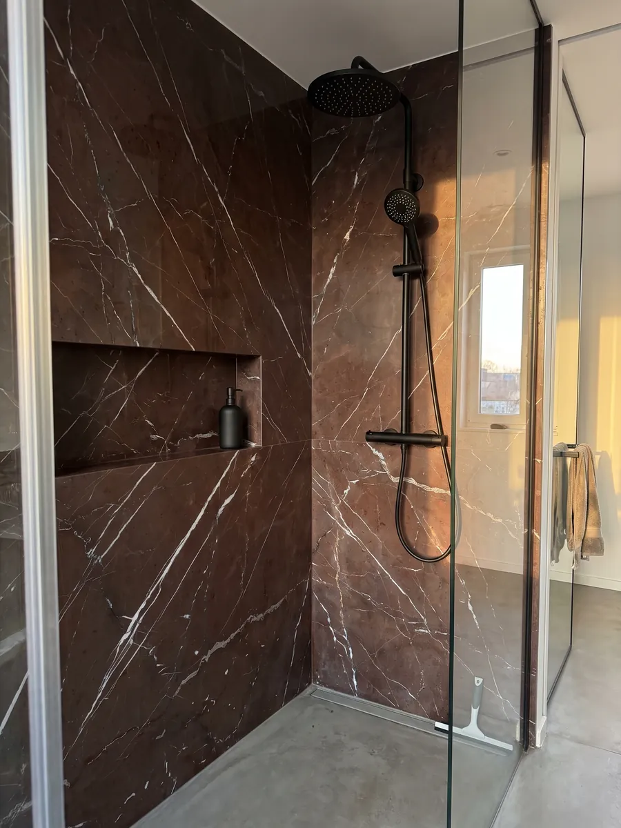 Shower clad in whole Rosso Collemandina marble slabs with a recessed niche: dark reddish brown with fine, straight, parallel white veins running diagonally