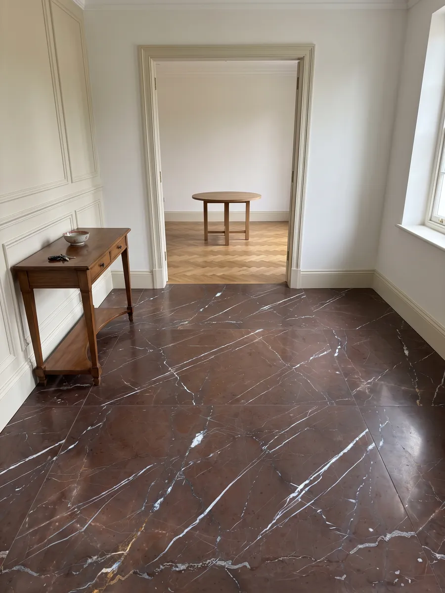 Entryway floor in large Rosso Collemandina marble slabs with natural light: dark reddish brown with fine, straight, parallel white veins running diagonally