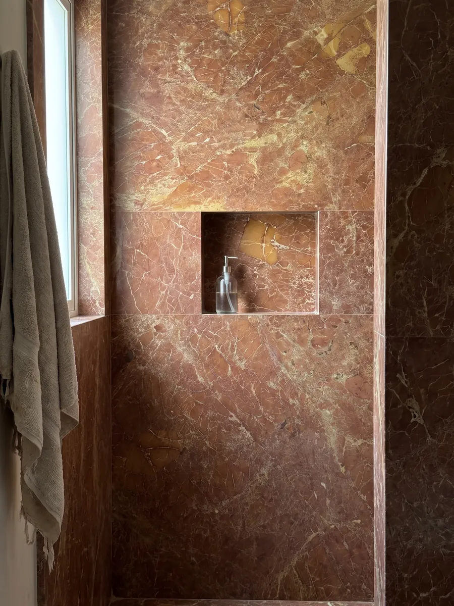 Shower clad in full red Melograno marble slabs with a recessed niche: brownish brick red with a fine network of light veins and ochre patches