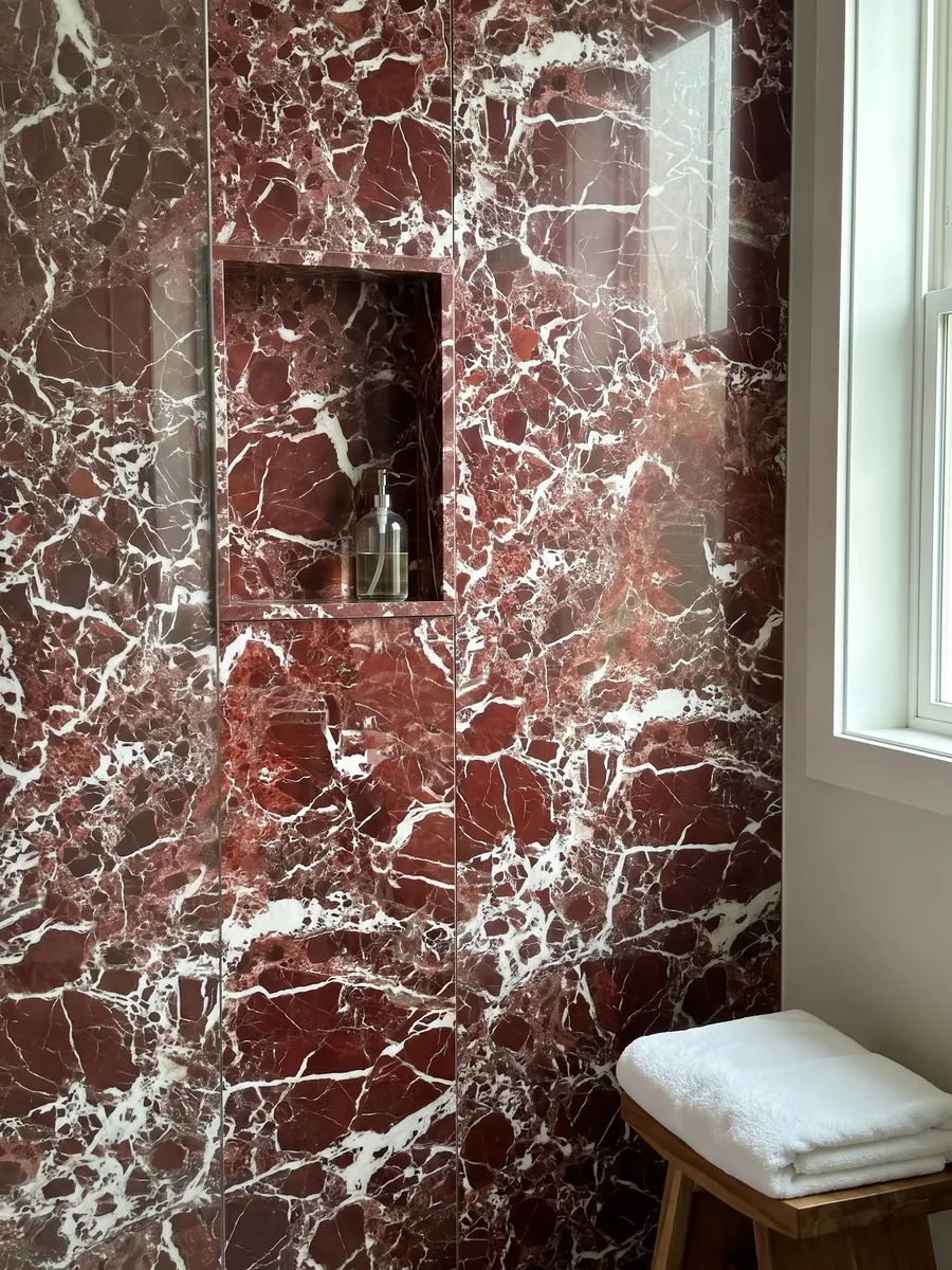 Shower clad in full slabs of red Rosso Lepanto marble with a recessed niche: intense red fragments surrounded by a dense network of white veins