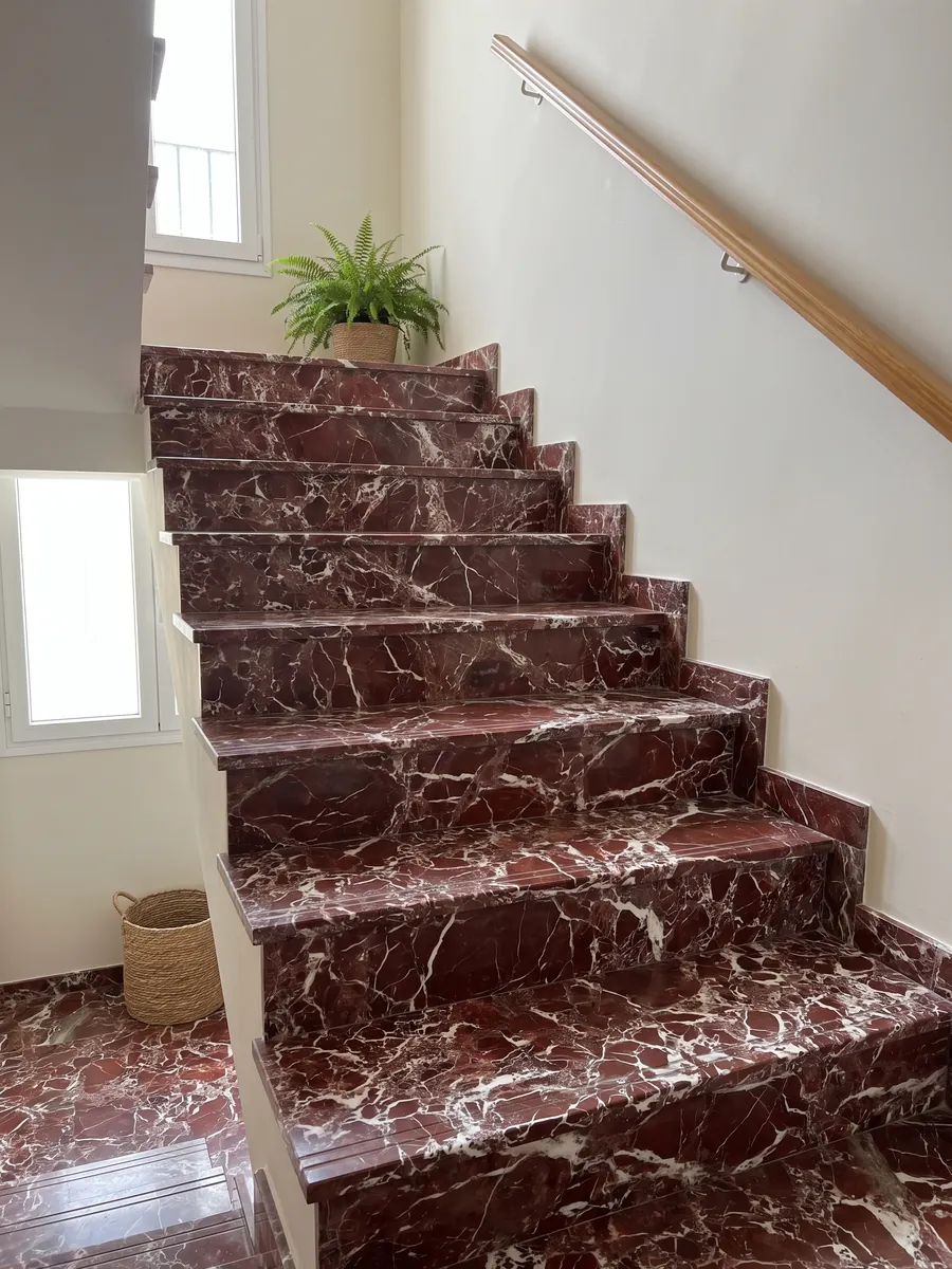Interior staircase with red Rosso Lepanto marble steps and a handrail: intense red fragments surrounded by a dense network of white veins