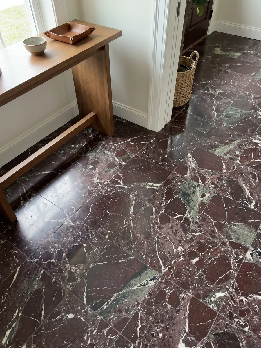Entryway floor in large slabs of red Rosso Levanto marble with natural light: dark burgundy with gray-green areas and a network of white veins