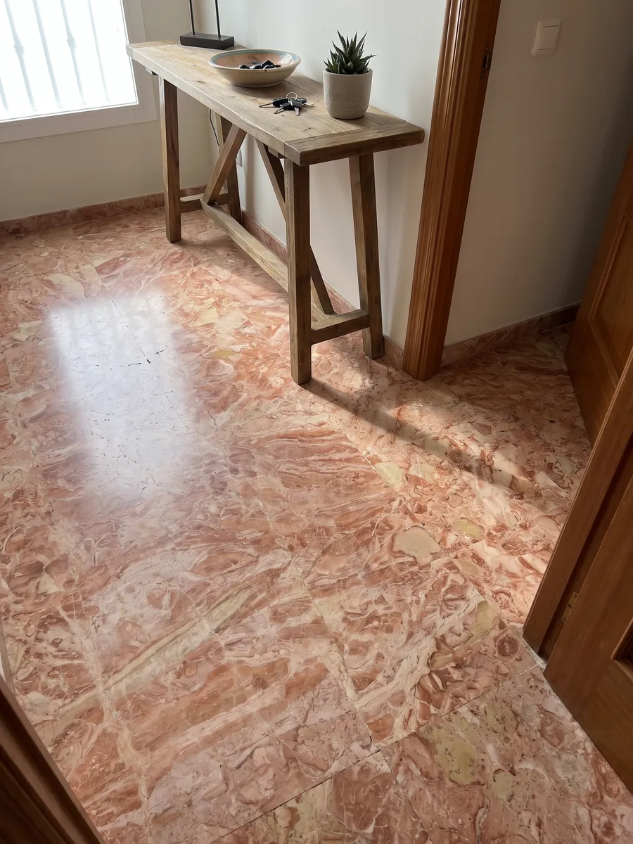 Entryway floor in large slabs of pink Breccia Bohemien marble with natural light: a dense mix of coral and light beige fragments in salmon tones