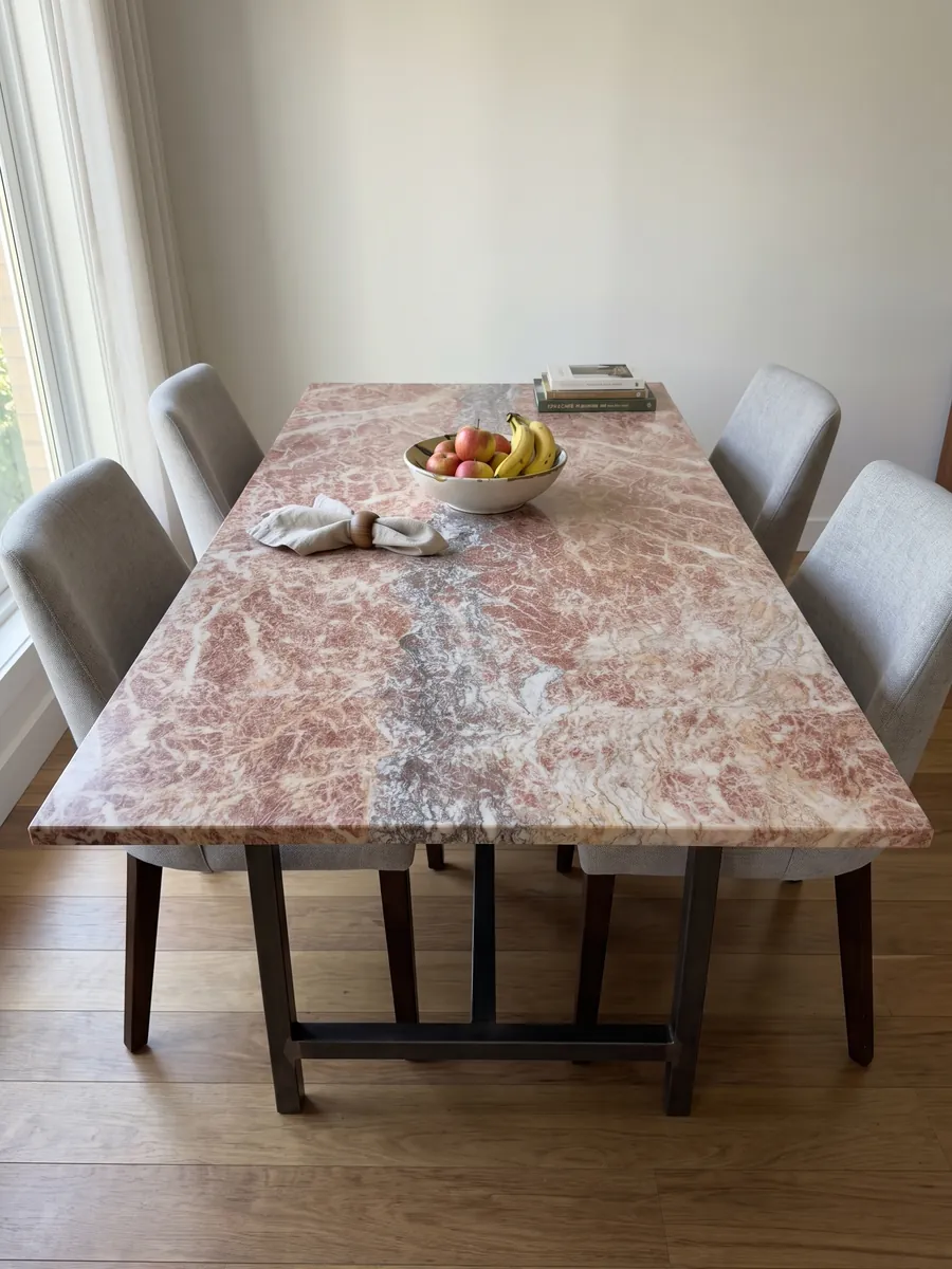 Dining table with a Rosa Peralba marble top on a steel base: reddish pink with a net of white veins and a vertical grayish-purple band