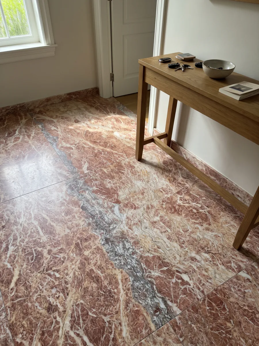 Entryway floor in large Rosa Peralba marble slabs with natural light: reddish pink with a net of white veins and a vertical grayish-purple band