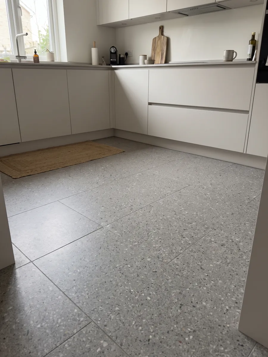 Kitchen floor in large slabs of Fior di Pesco Grey engineered marble with cement: medium gray with small white and dark fragments, fine terrazzo style