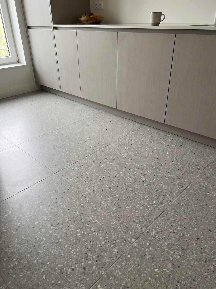 Kitchen floor in large slabs of Fior di Pesco Grey engineered marble with resin: light gray dotted with many small white fragments, terrazzo style