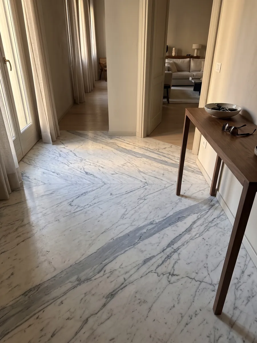 Entryway floor in large slabs of Statuarietto marble with natural light: white with bluish gray veins running diagonally