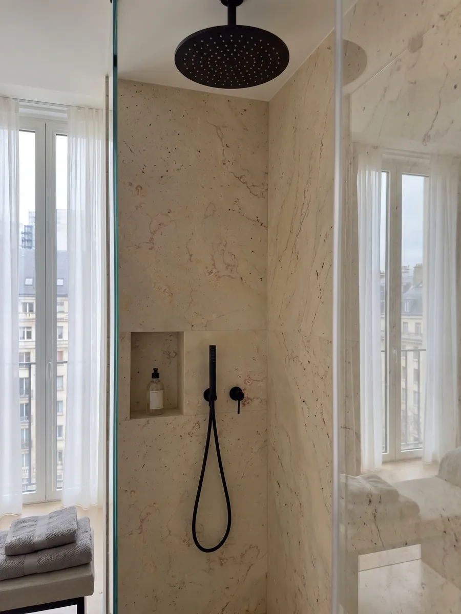 Shower clad in full slabs of Trani Filetto Rosso marble with a recessed niche: cream background with fine sinuous reddish filaments and small isolated dark spots