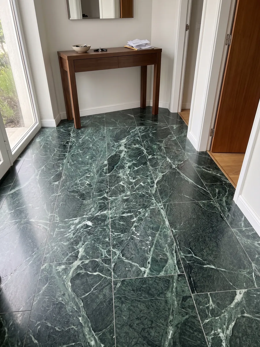 Piso de hall de entrada em placas grandes de Mármore Verde Alpi com luz natural: verde quase preto atravessado por uma rede densa de veios verde-claro e brancos