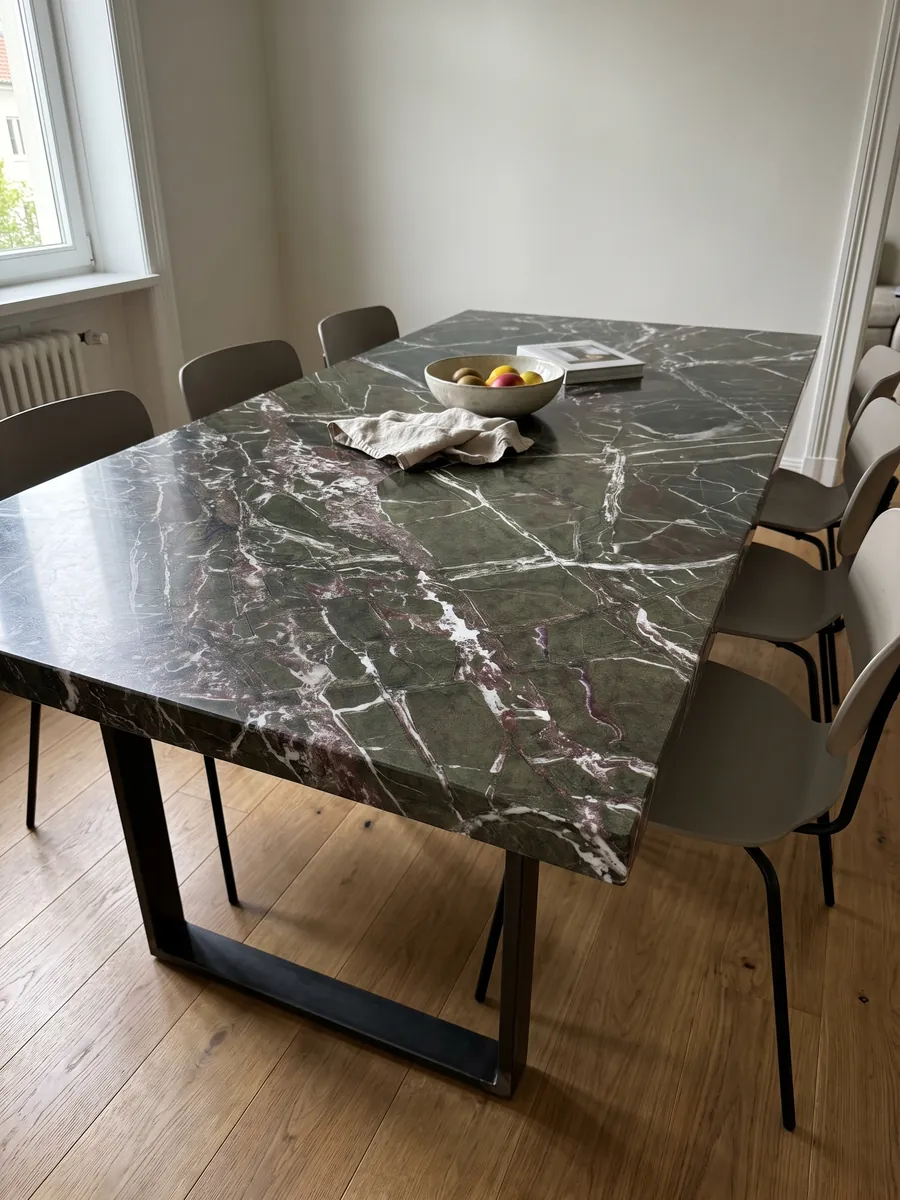 Dining table with a Breccia Imperiale green marble top on a steel base: dark green with a web of straight white veins and small wine-red touches