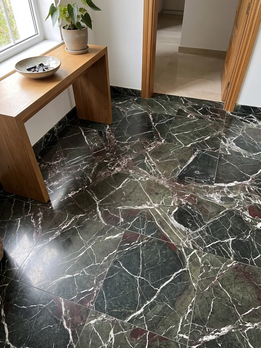 Entryway floor in large Breccia Imperiale green marble slabs with natural light: dark green with a web of straight white veins and small wine-red touches