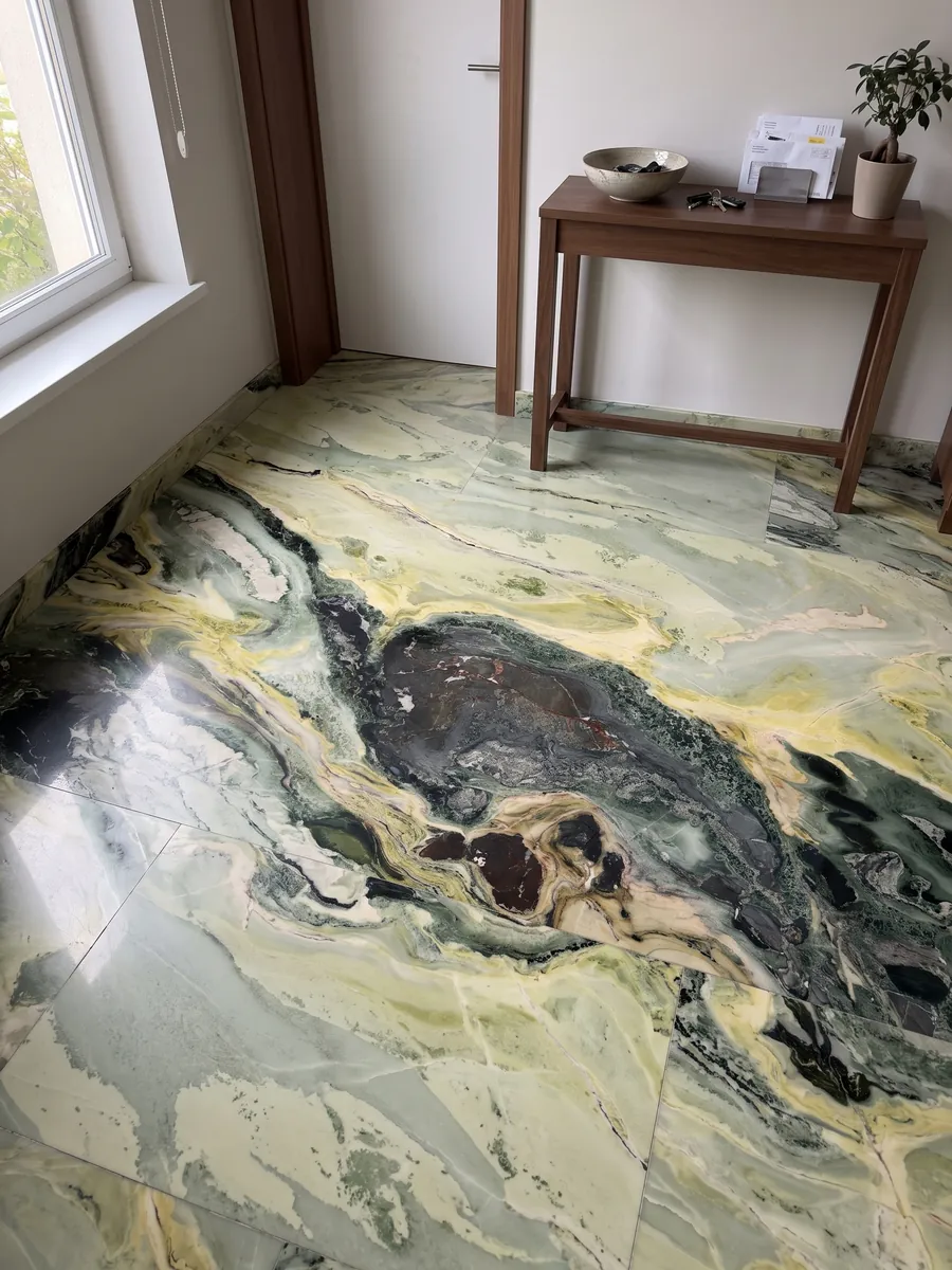 Entryway floor in large slabs of green Dream Green marble with natural light: dark green and lime yellow waves with a very dark central area