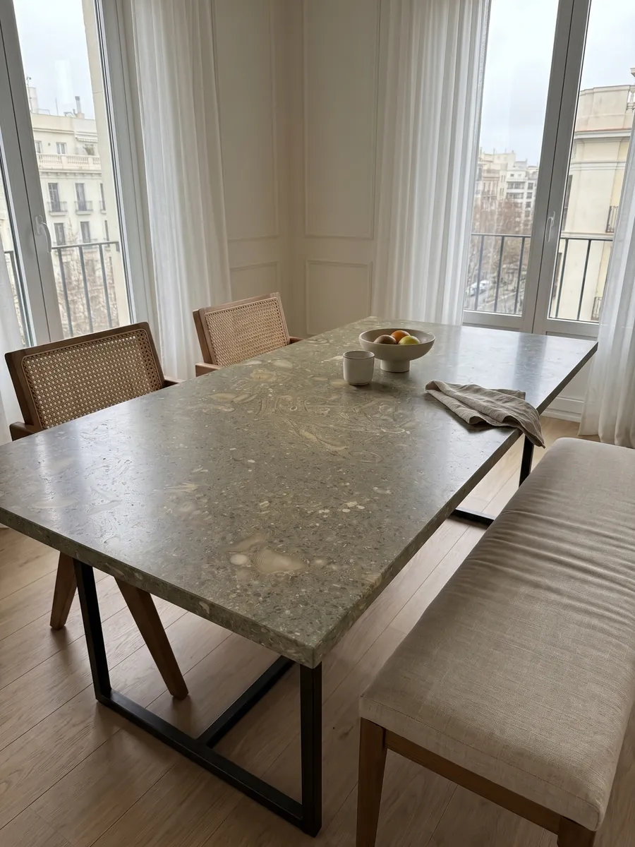 Dining table with a green Fossil Green marble top on a steel base: speckled olive green with fossil shell silhouettes in a lighter tone
