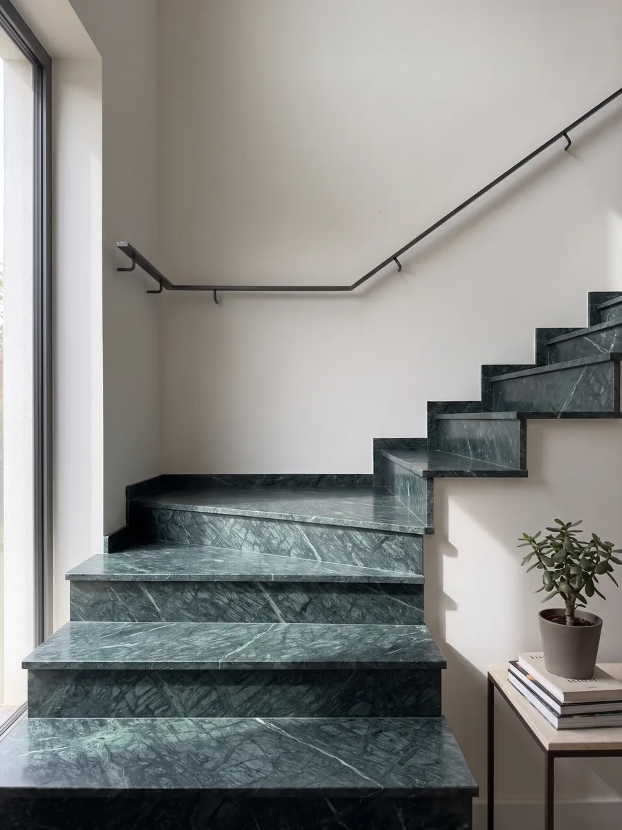 Interior staircase with Verde Imperiale marble treads and a handrail: deep petrol green with fine lighter veins crossing on the diagonal