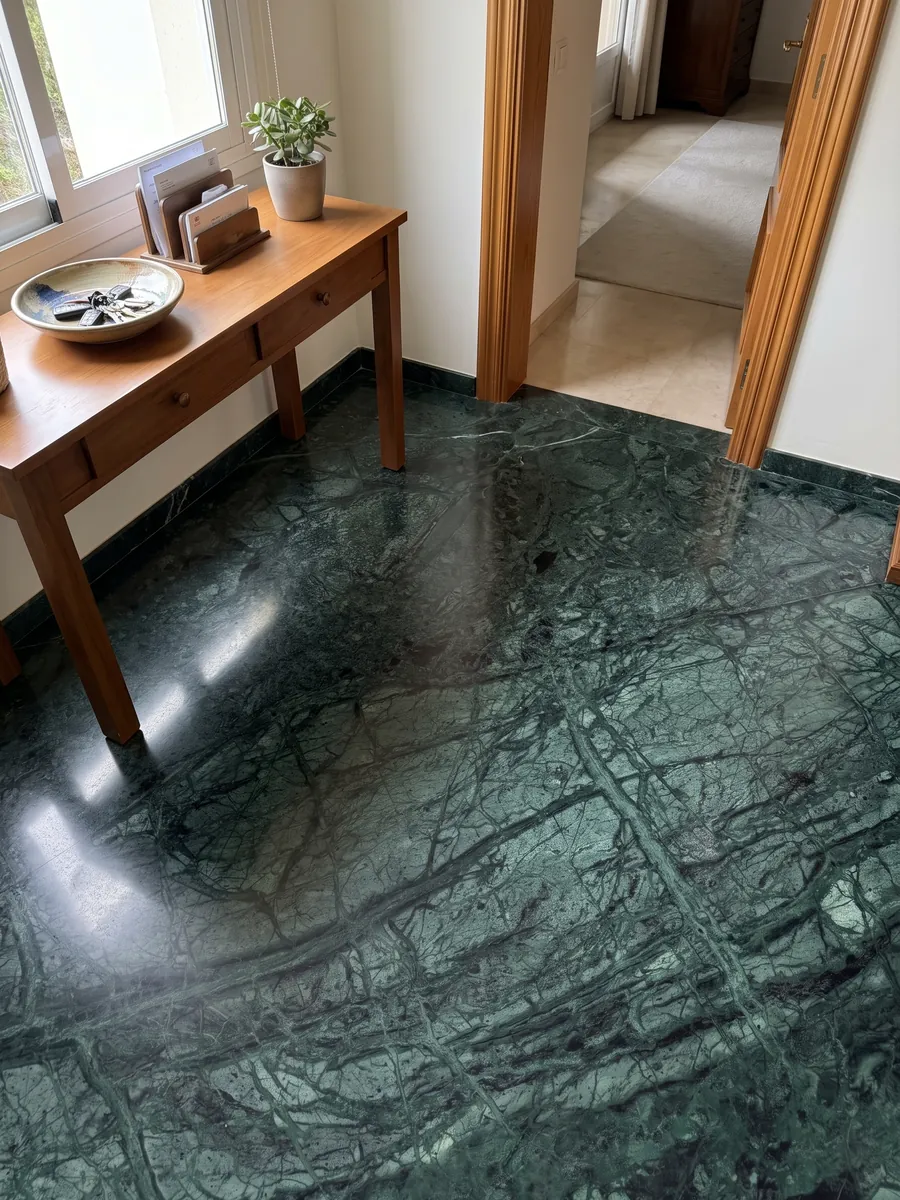 Entryway floor in large Verde Imperiale marble slabs with natural light: deep petrol green with fine lighter veins crossing on the diagonal