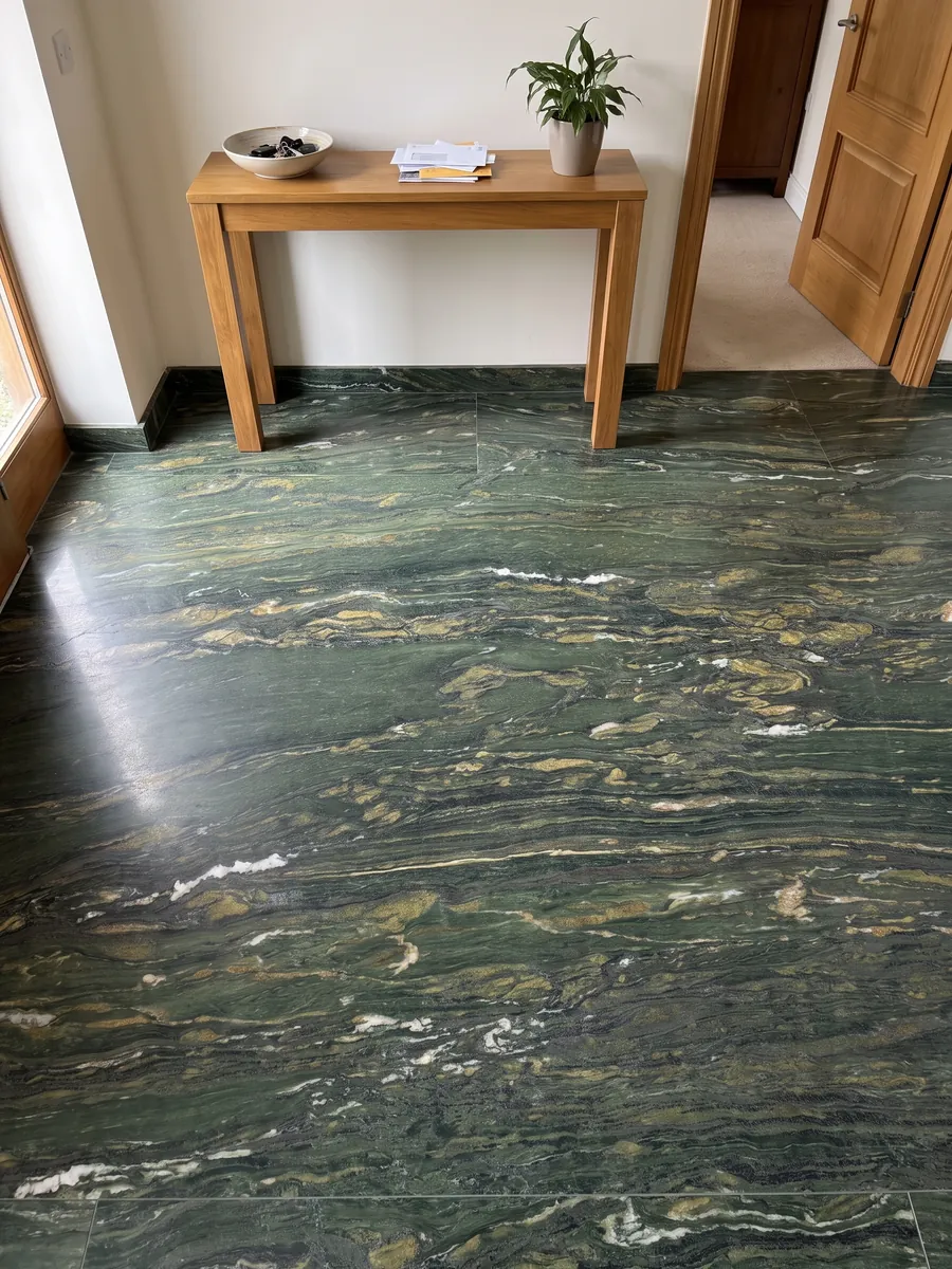 Entryway floor in large Verde Pavone marble slabs with natural light: deep green with golden and white strokes flowing horizontally