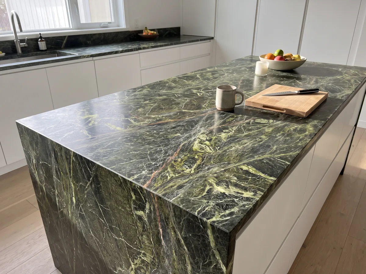 Kitchen island with a Rainforest Green marble countertop and a straight edge in a kitchen with natural light: dark green covered by a dense web of yellow-green veins