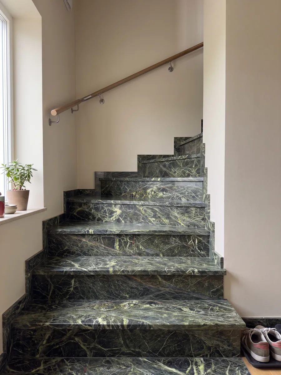 Interior staircase with Rainforest Green marble steps and a handrail: dark green covered by a dense web of yellow-green veins