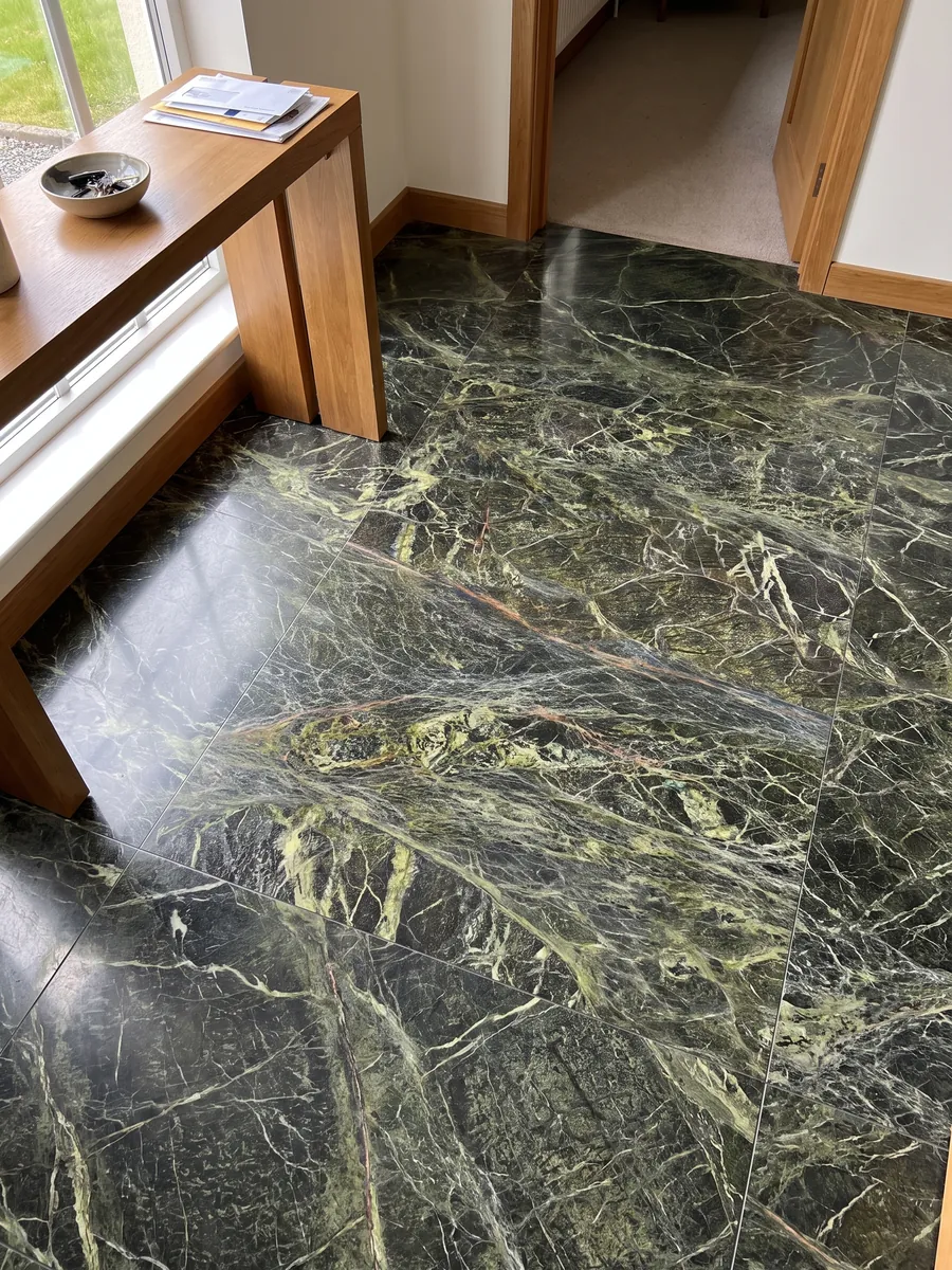 Entryway floor in large slabs of Rainforest Green marble with natural light: dark green covered by a dense web of yellow-green veins