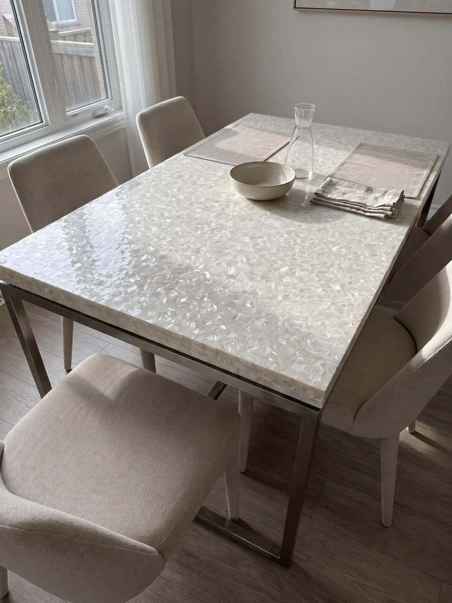 Dining table with a freshwater shell mother of pearl top on a steel base: an almost uniform pearly white with very small mother-of-pearl pieces