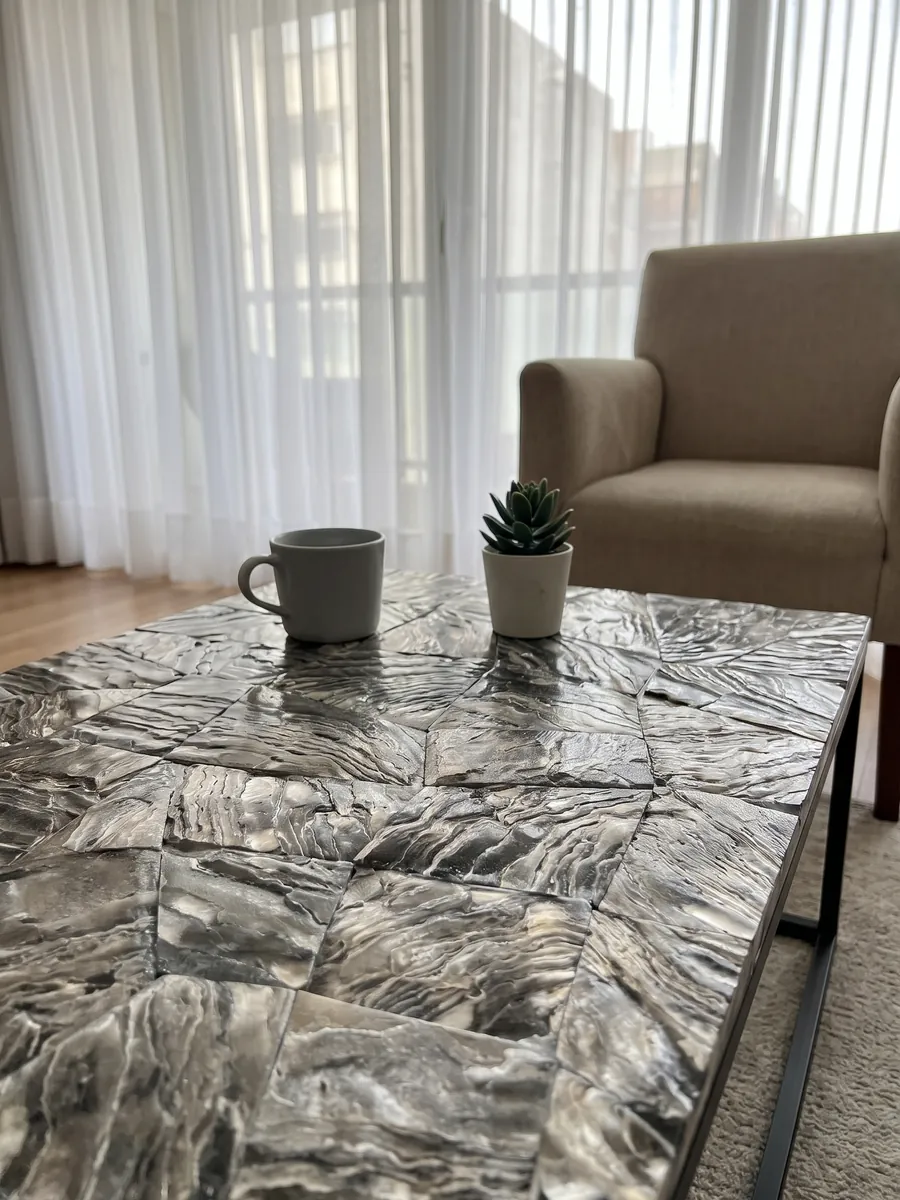 Coffee table with a Galushell Gray Mother of Pearl top in a living room: gray-silver shell pieces with wavy, metallic-looking striations