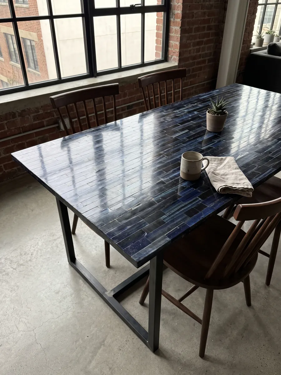 Dining table with a blue tiger's eye top on a steel base: horizontal bands of almost black navy with blue flashes