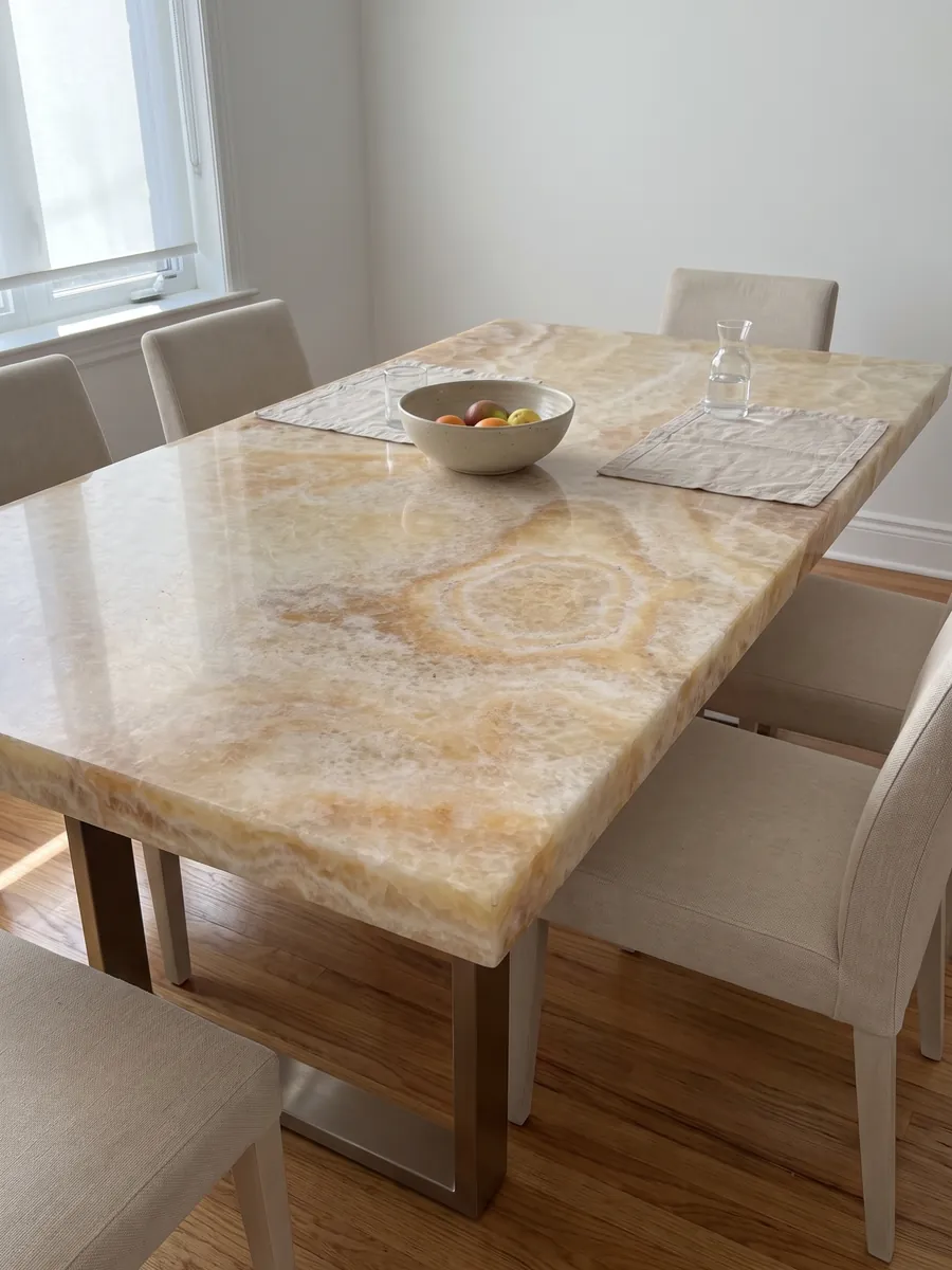 Dining table with a yellow onyx top on a steel base: honey and cream with a clearly visible concentric oval ring