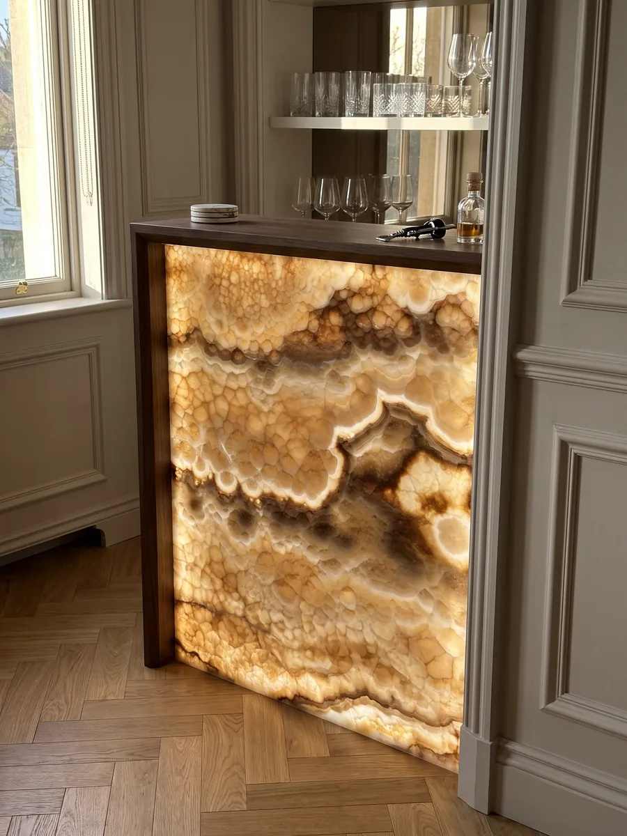 Bar with a backlit dark honey onyx front, the light passing through the stone: amber with a rounded-cell texture and wavy dark brown bands