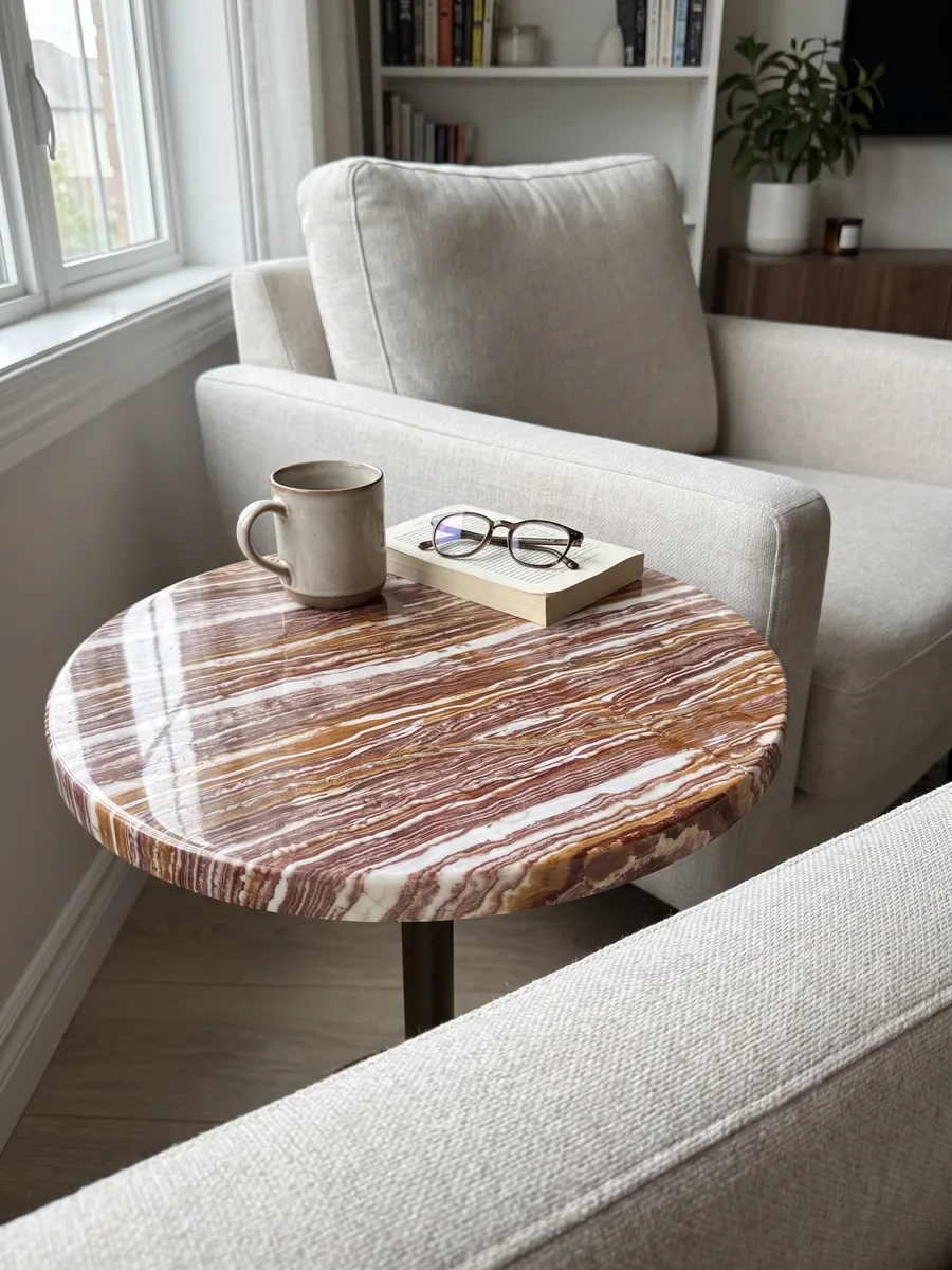 Side table with a brown Fantastico onyx top next to an armchair: strongly marked alternating horizontal bands of white, reddish and ochre