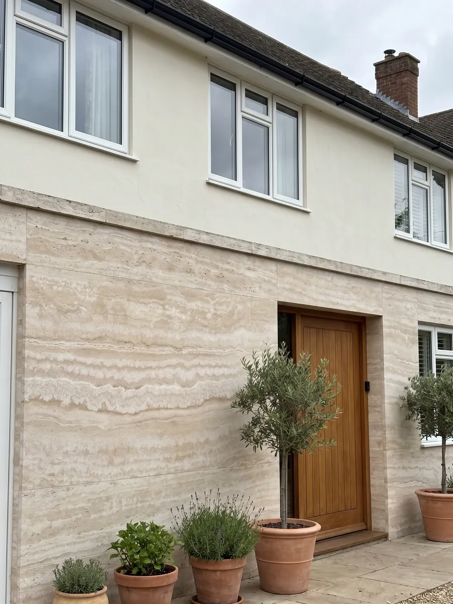 House facade clad in beige Paglierino travertine next to a wood door: cream with wavy horizontal bands in very close tones