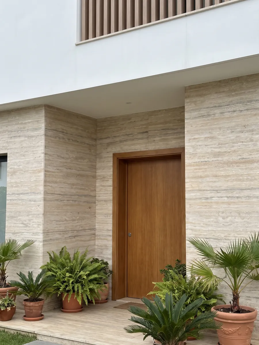 House facade clad in gray Ocean Silver travertine next to a wood door: fine beige and gray horizontal stripes with some pores