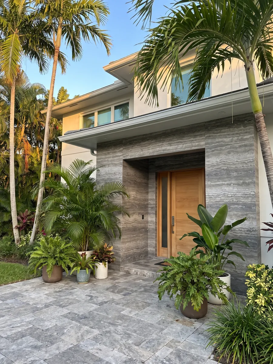 House facade clad in gray Titanium travertine next to a wooden door: gray with wavy horizontal bands that move from light to dark