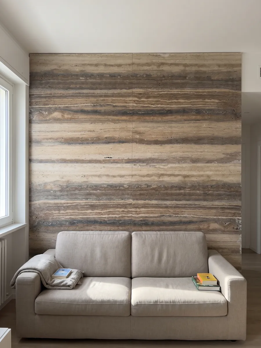 Living room wall clad in bookmatched brown Dark Silver travertine slabs behind a sofa: strongly marked brown and beige horizontal bands running along the slab