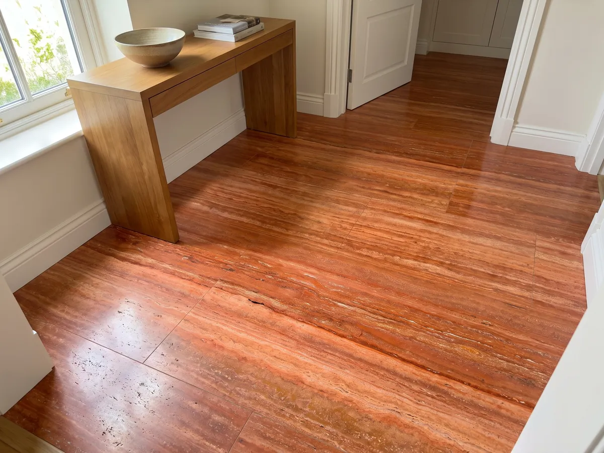 Entryway floor in large red travertine tiles with natural light: intense orange-red in horizontal bands with fine cream lines