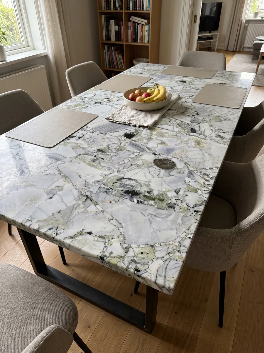 Dining table with a White Beauty top on a steel base: white and gray fragments joined by light green areas, with loose black pieces