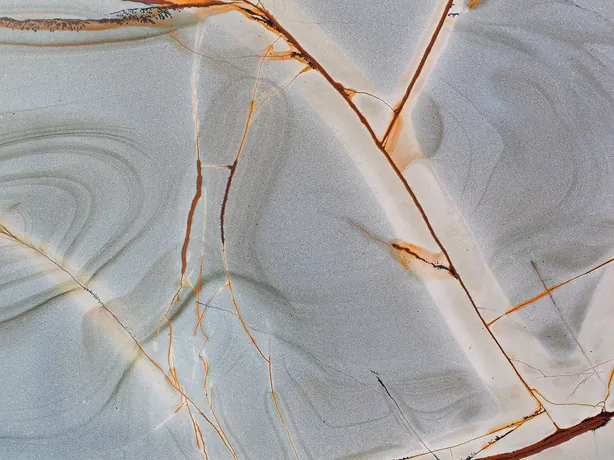 Blue Roma quartzite detail: reddish branches and gray concentric rings with a polished gloss