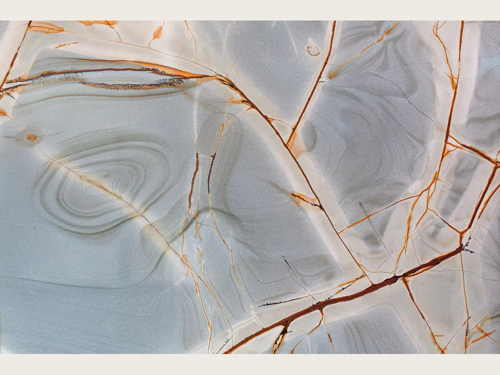 Blue Roma quartzite slab: light grayish blue background with fine rust red and orange branches